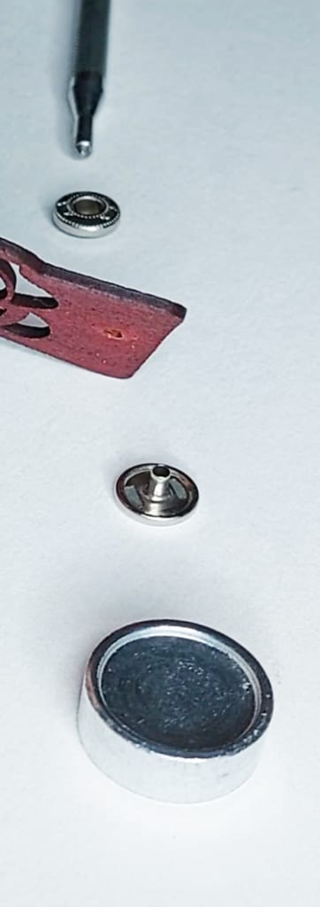 Placement of each piece Shows the correct placement of each component, layered from bottom to top: base, button, leather, socket, pointed installation tool.